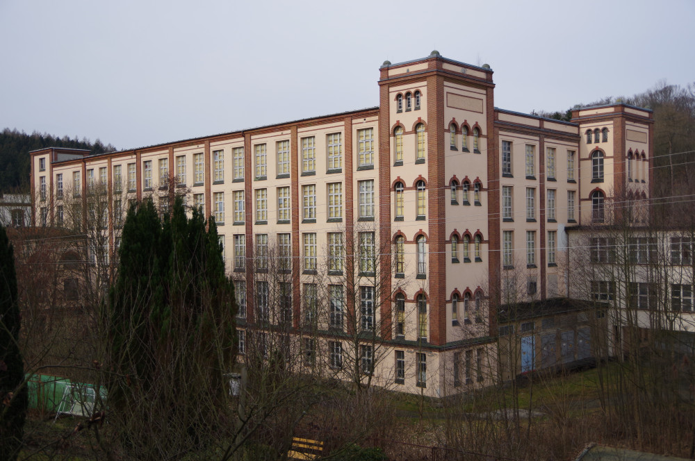 großes Haus mit spitzem Turm und grauem Schieferdach aus einer untersichtigen Perspektive fotografiert